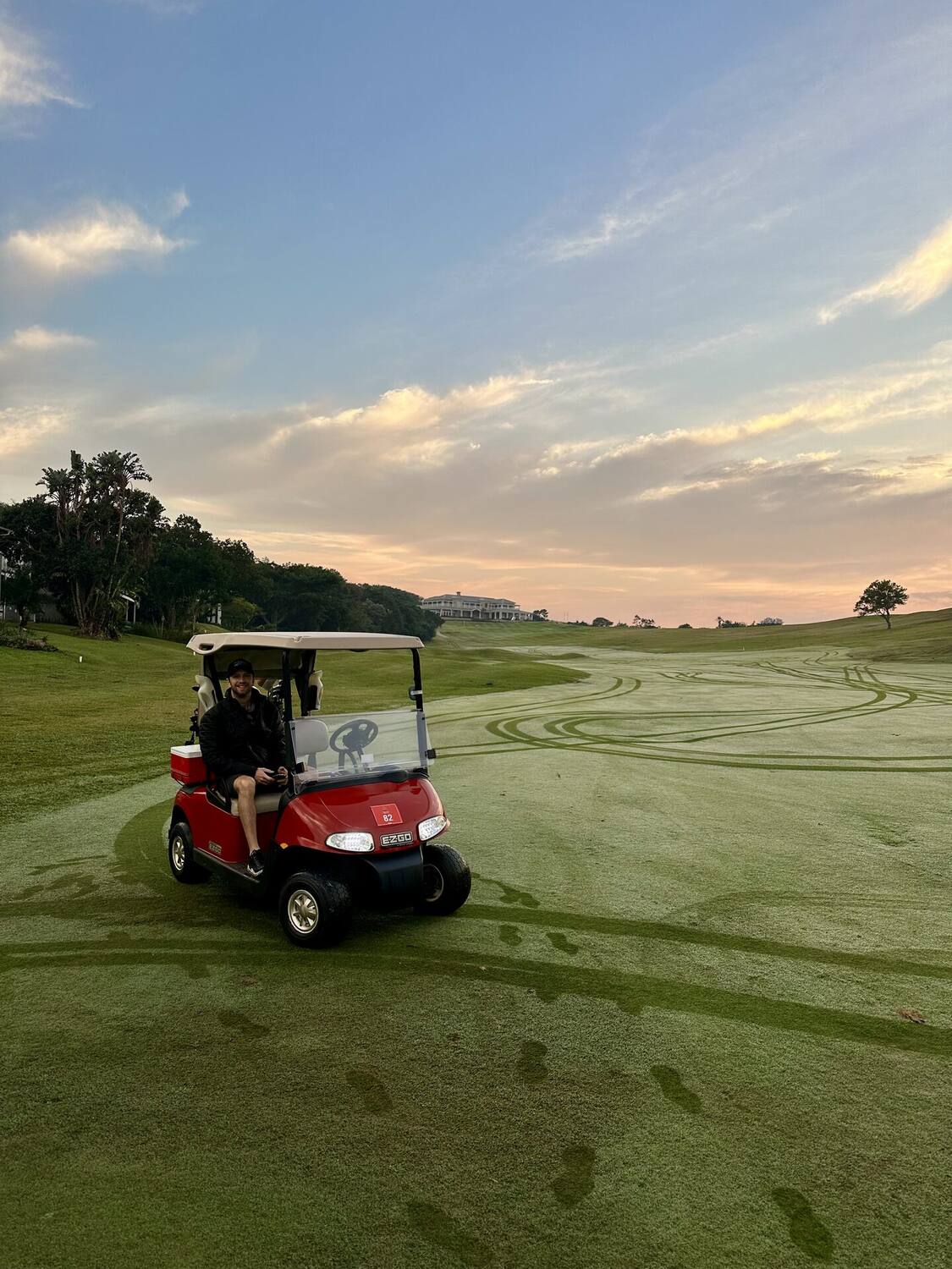 Golf cart on the fairway at sunset with the clubhouse behind